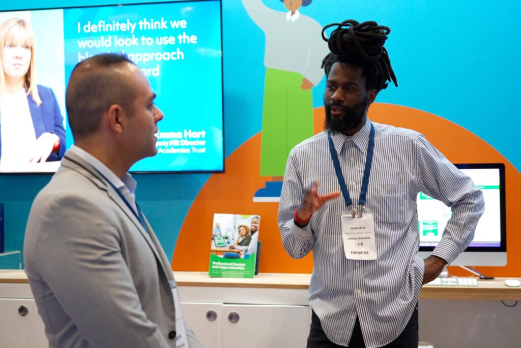 A Mindful Education Employee speaking to a delegate at an industry event about Mindful Education's blended learning courses and apprenticeships.