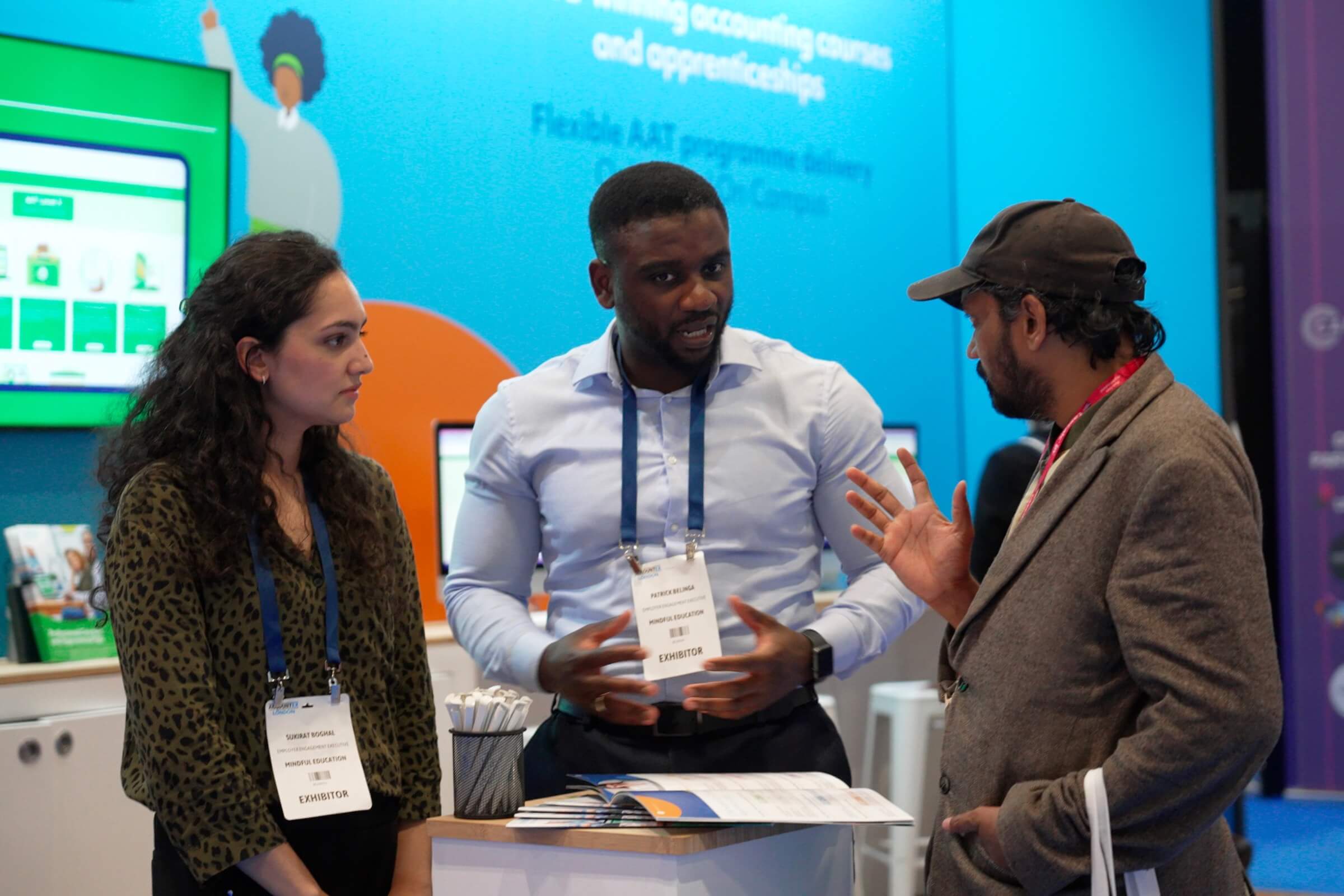 Two Mindful Education employees engaged in a conversation with a delegate at an industry event.