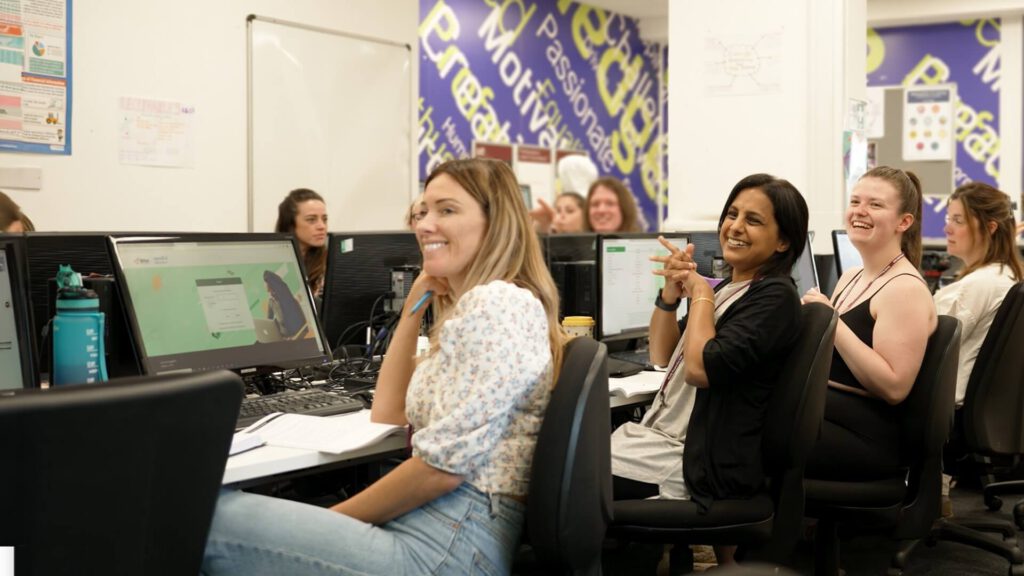 Online and On Campus learners sitting in a classroom and listening to a professional tutor explain course content to them.