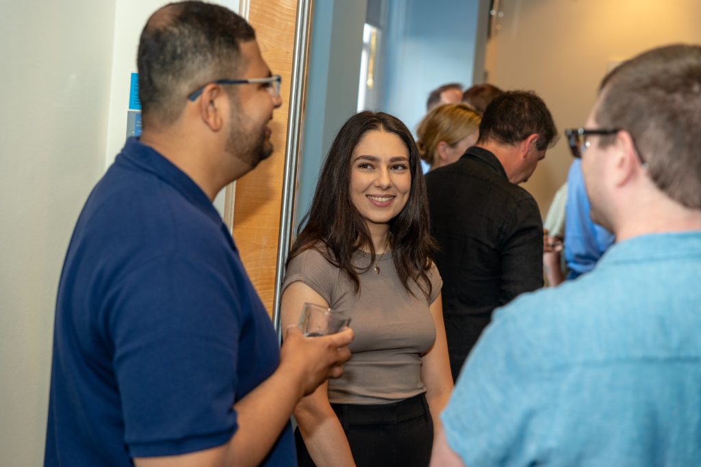 Three Mindful Education employees standing whilst engaging in a conversation.