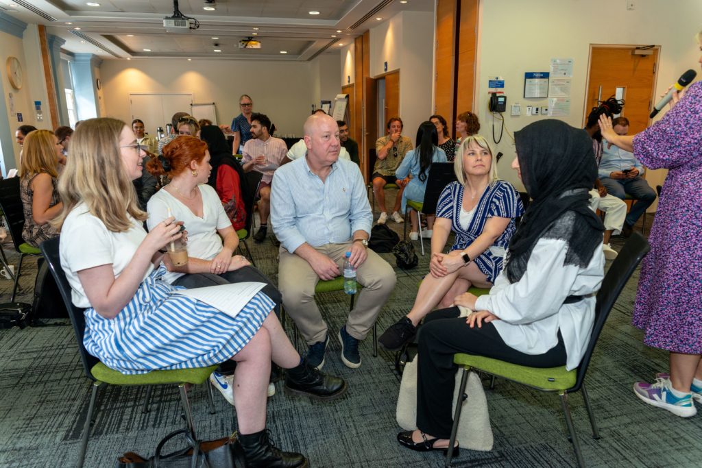 An image of five Mindful Education employees working together to answer quiz questions at the annual company Summer Conference.