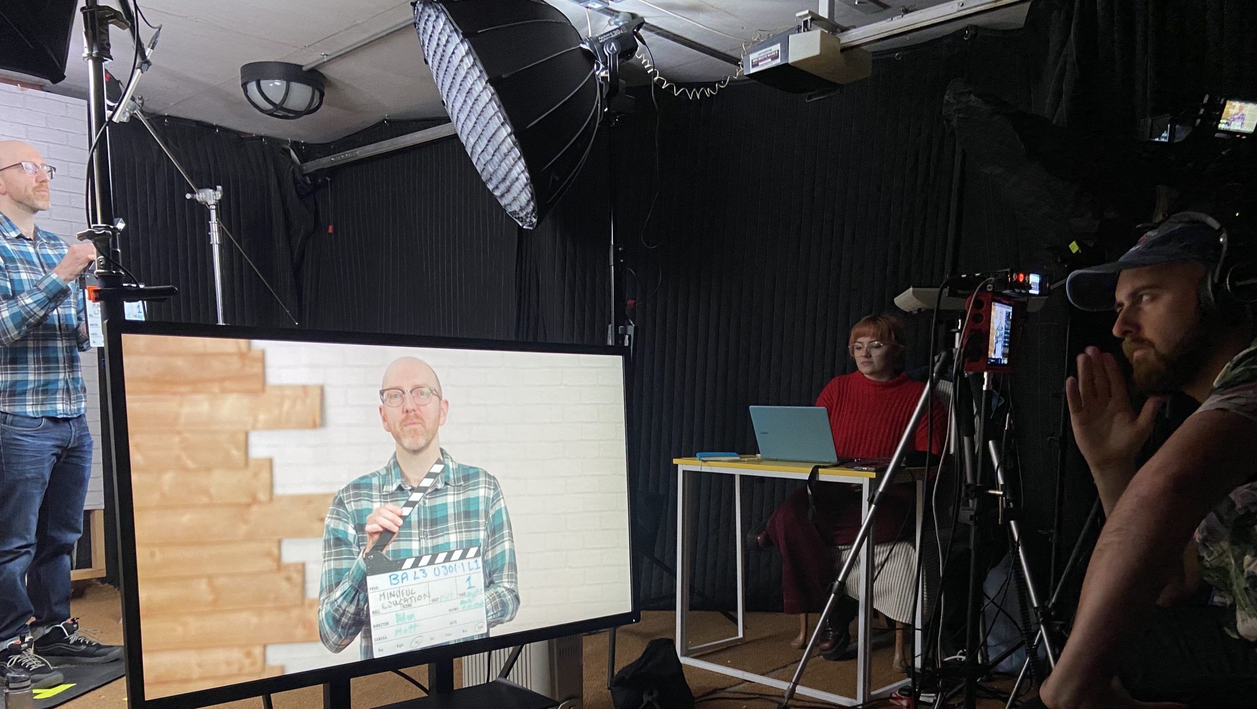 A behind the scene image of filming for the Mindful Education course and apprenticeship videos, featuring a Mindful Education Academic holding a clapperboard.