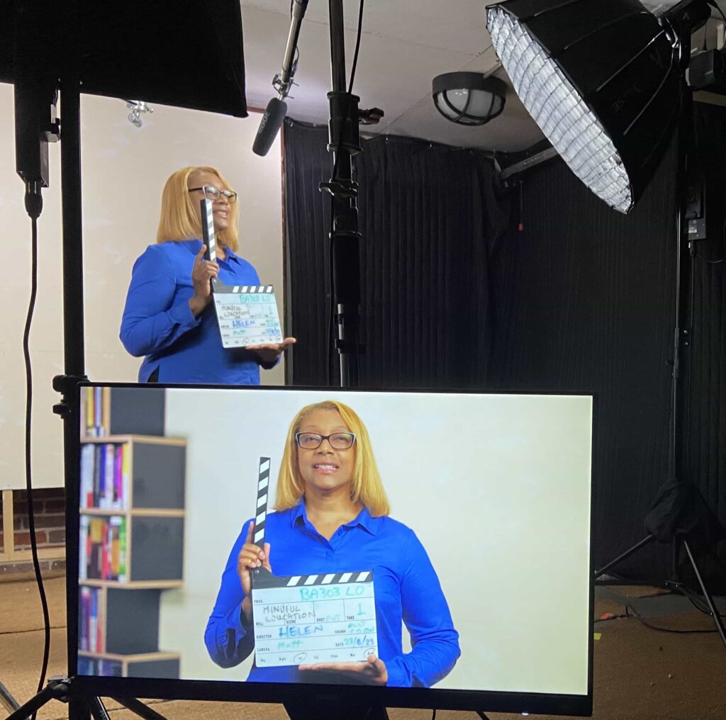 A picture showing a member of the Mindful Education production team in a filming studio, holding a clapperboard.