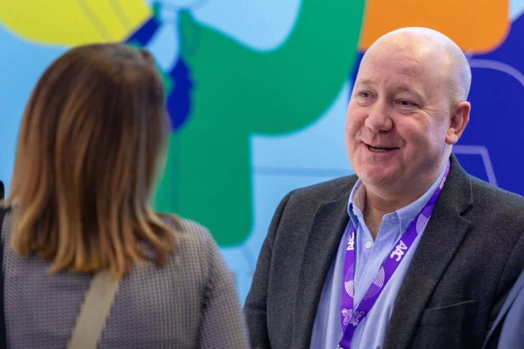 A Mindful Education employee at an industry event speaking to a delegate about Mindful Education's professional, award-winning courses and apprenticeships.