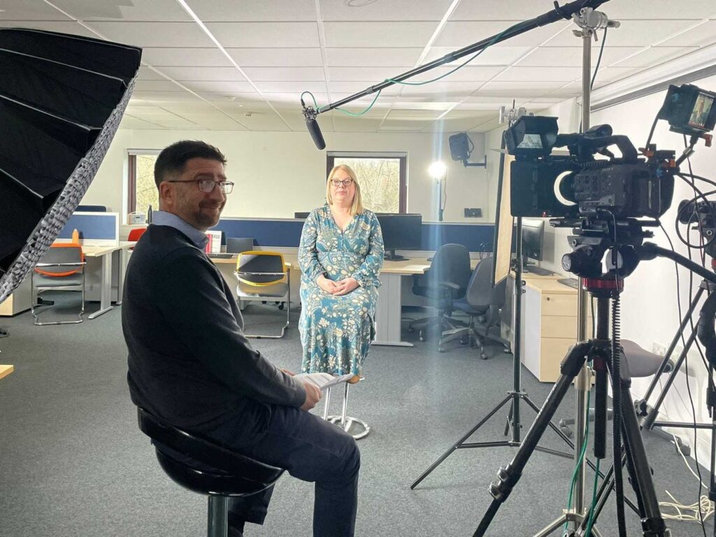 A Mindful Education employee and individual from a large organisation smiling at a camera.