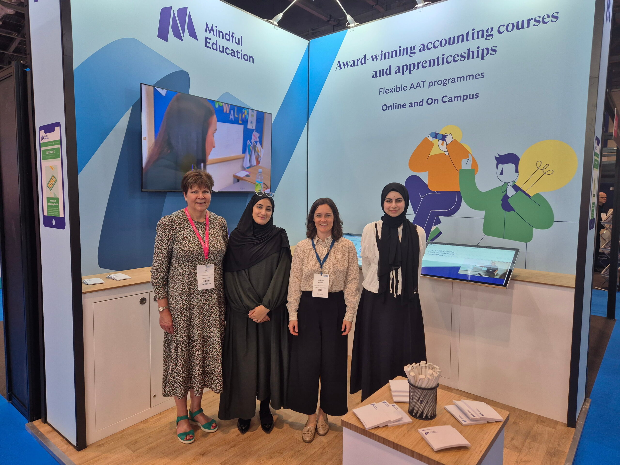 Four members of the Mindful Education team in front of their exhibition stand at Accountex London.